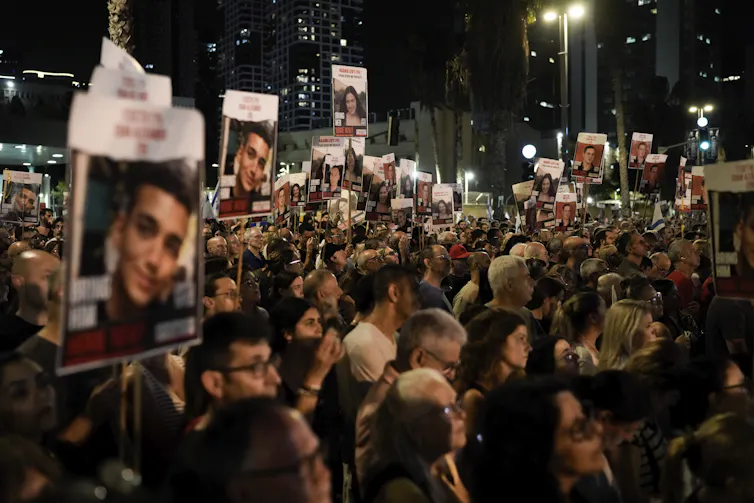 Protestors with the faces of Israeli hostages on placards.