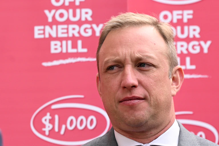 A man looks to the side in front of bright red signage