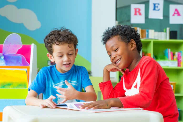 Two boys looking at book together in brightly coloured classroom