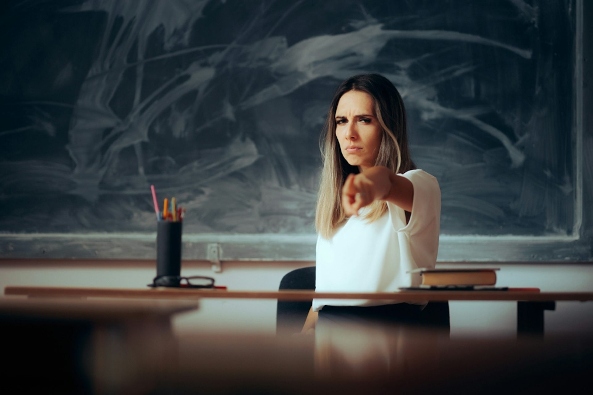 Une enseignante en colère assise à son bureau face à une classe