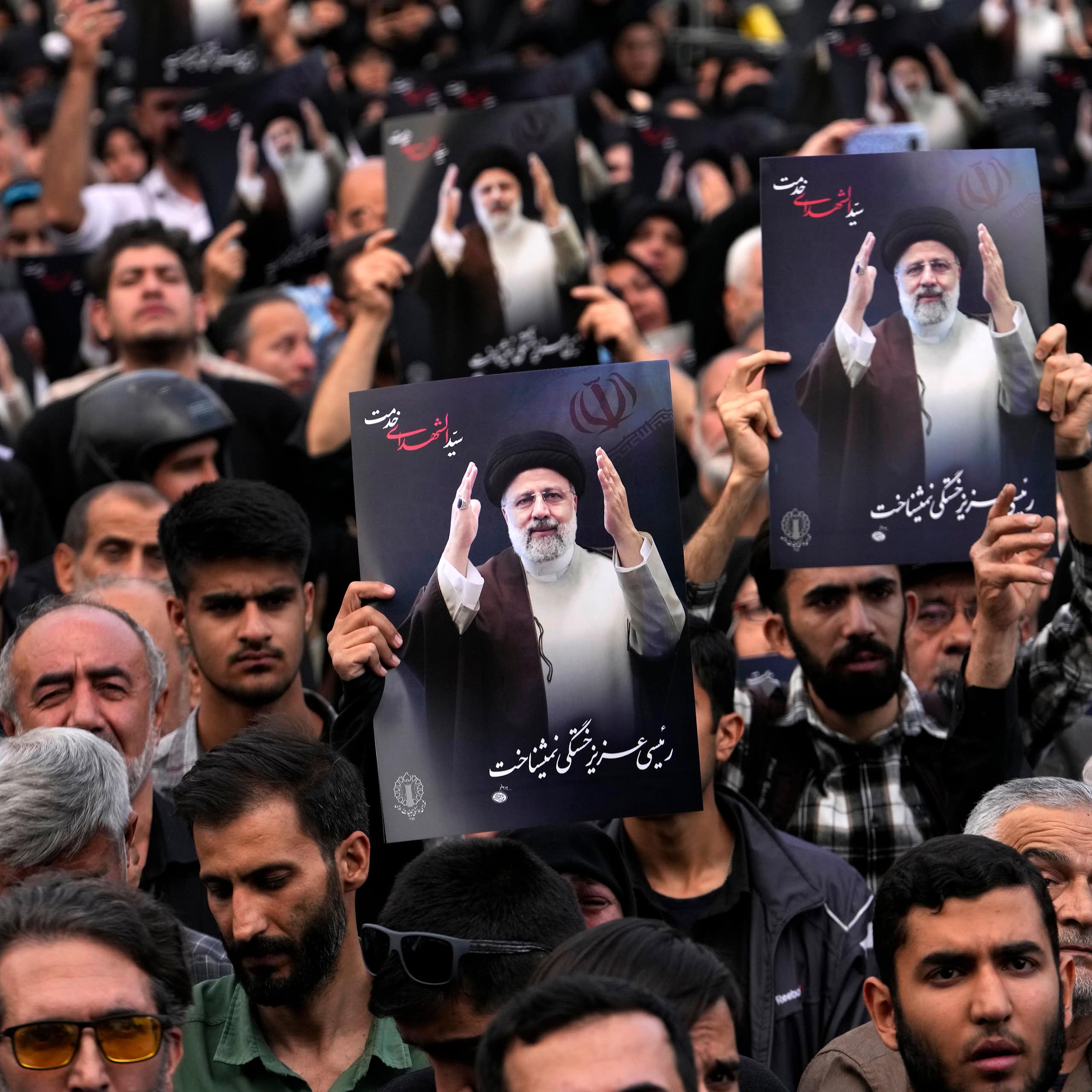 People hold up posters with pictures of a man in a black robe and turban with words below written in Persian.