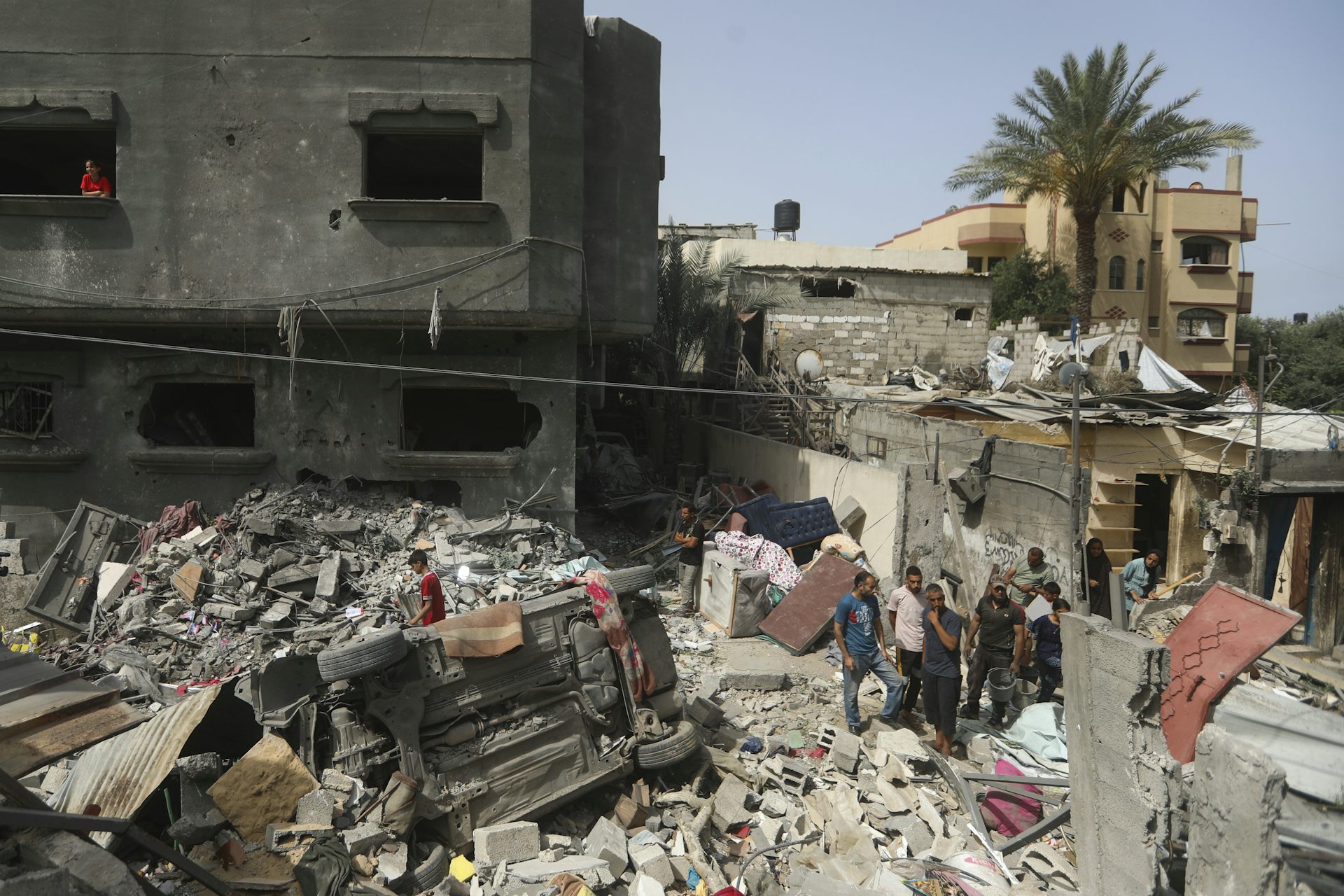 People look at a pile of rubble from a destroyed building.
