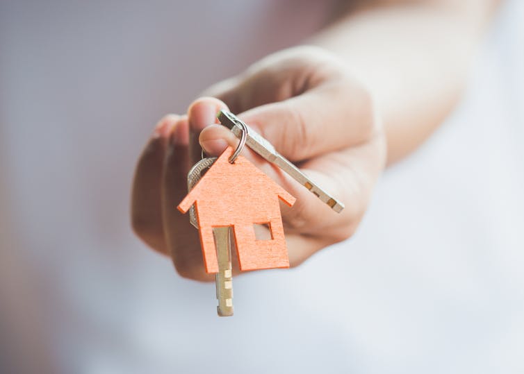 Close up of a hand holding a set of keys with a house-shaped keyring.