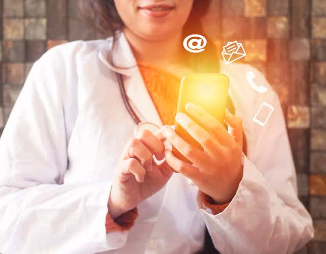 Cropped image of woman in a white coat holding a phone 