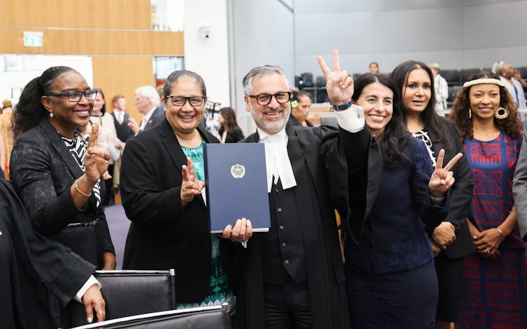 Members of the Commission of Small Island States on Climate Change and International Law make the victory sign and hold the legal opinion of the International Tribunal for the Law of the Sea.