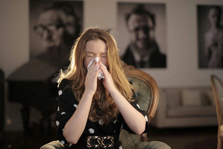 A woman blows her nose into a tissue
