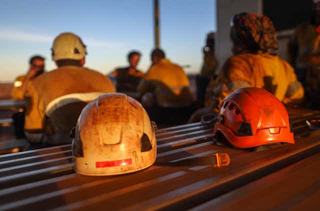 Miner safety helmets on a table with blurred figures in the background
