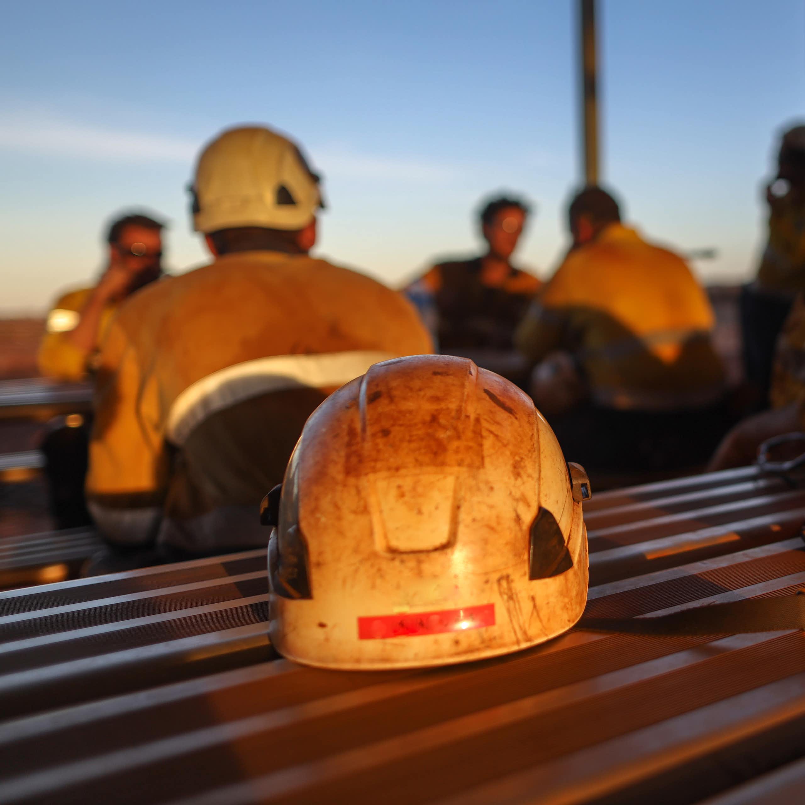 Miner safety helmets on a table with blurred figures in the background