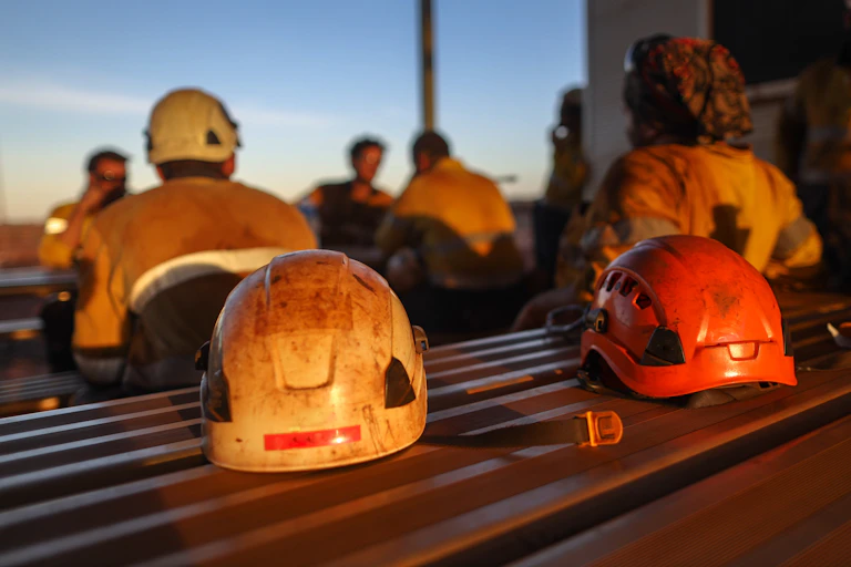 Miner safety helmets on a table with blurred figures in the background