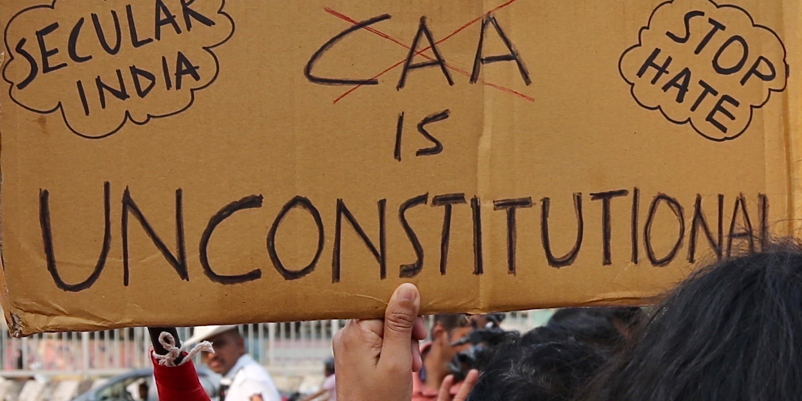 A protester holds up a banner that says 'CAA is unconstitutional'