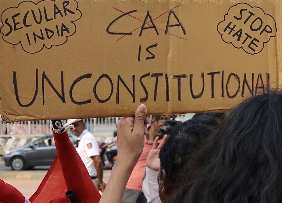 A protester holds up a banner that says 'CAA is unconstitutional'