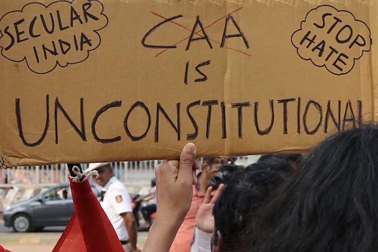 A protester holds up a banner that says 'CAA is unconstitutional'