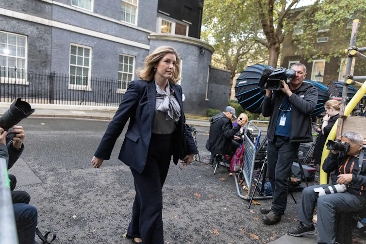 Penny Mordaunt walking into Downing Street, while photographers on either side of her take photos