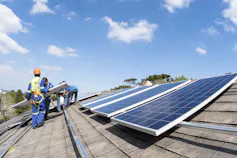 Men place solar panels on a roof. It is clear that there is no security system to prevent these panels from later being stolen.