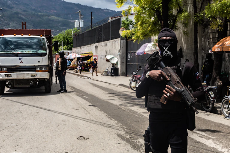 A policeman dressed in black with his face covered holding a gun.