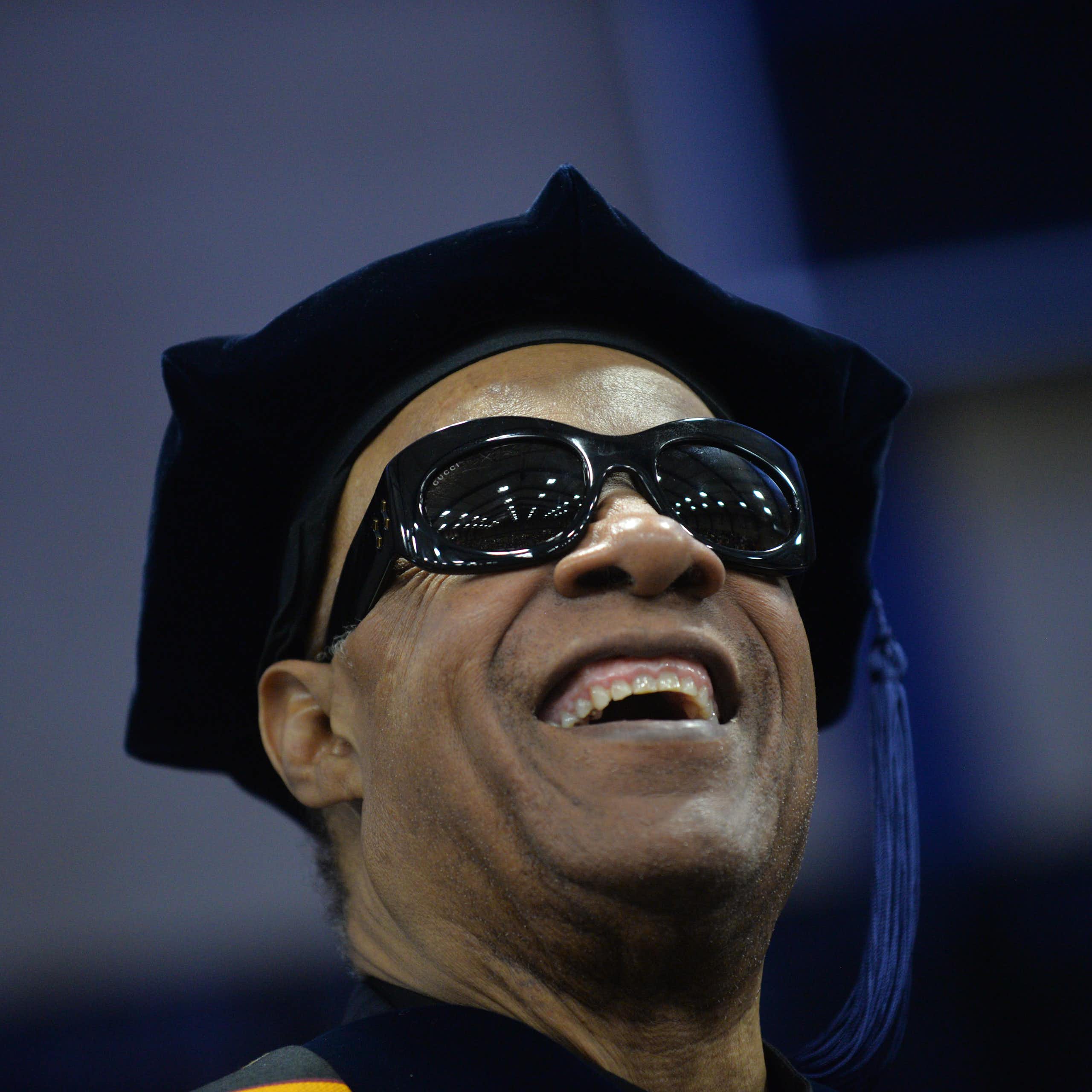 Smiling man wearing dark glasses and a black cap with a tassel