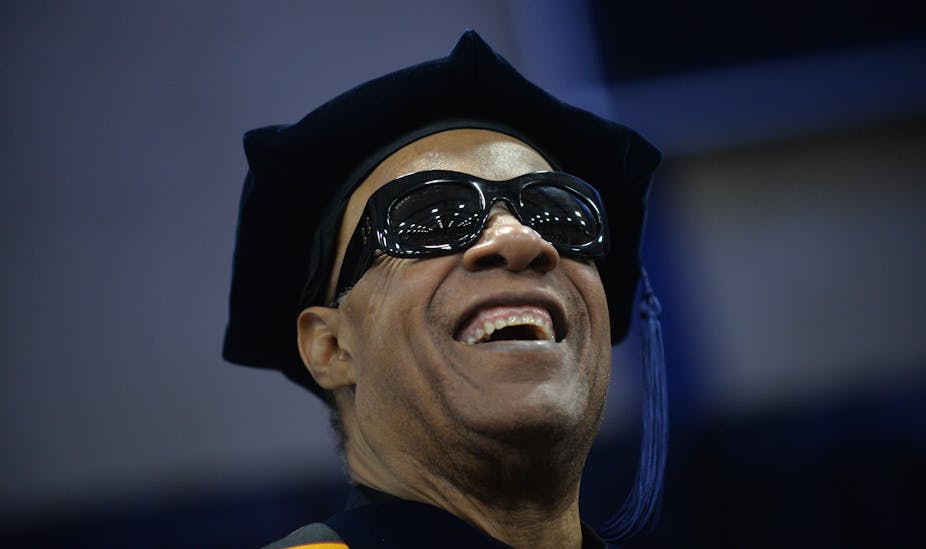 Smiling man wearing dark glasses and a black cap with a tassel