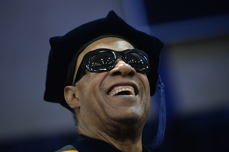 Smiling man wearing dark glasses and a black cap with a tassel