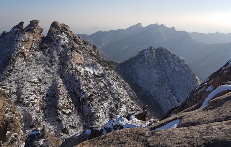 A mountainous landscape smattered with a dusting of snow.