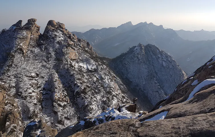 A mountainous landscape smattered with a dusting of snow.