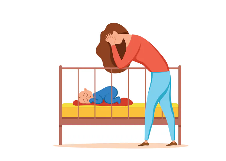 A mother cowers over her child's crib.