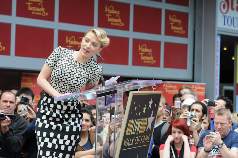 a white woman in a black and white outfit stands at a podium