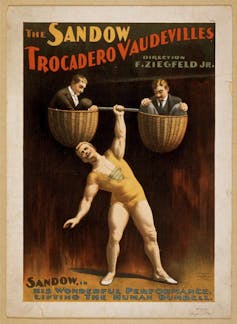 A poster for a strongman event showing a mostly naked man holding up two men in baskets with one hand.