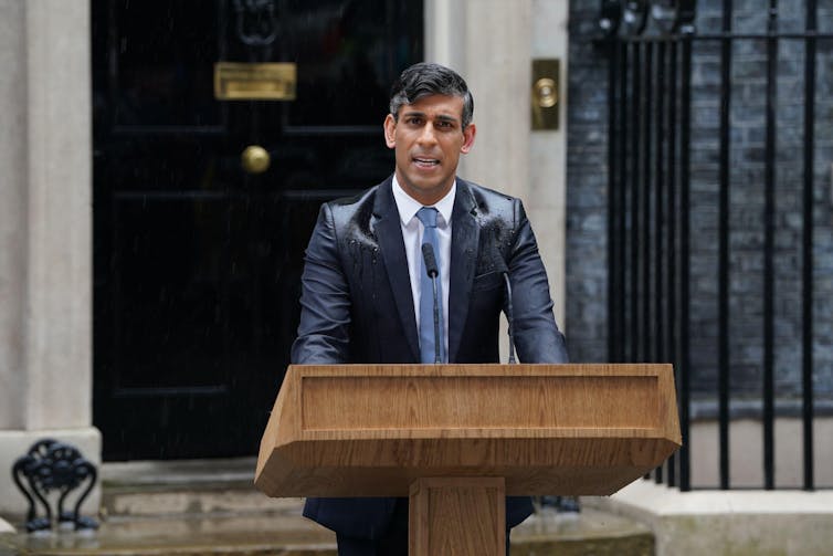 Rishi Sunak fazendo um discurso na chuva