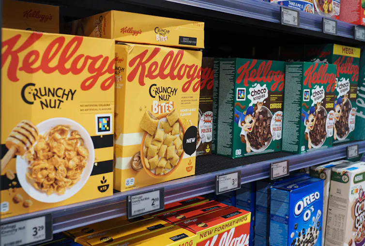 A row of brightly colored Kellogg's cereal boxes sit on a grocery store shelf.