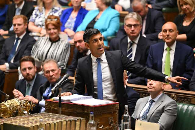 Rishi Sunak standing at the dispatch box and speaking in the house of commons, while pointing emphatically to his left