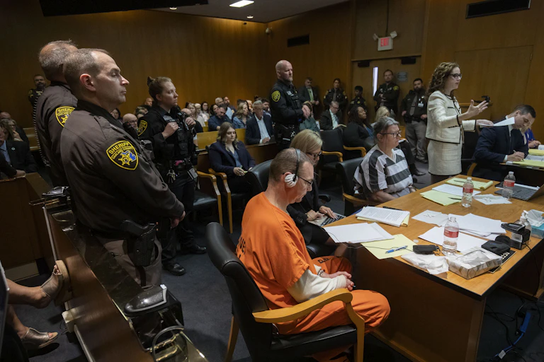 Man in orange jumpsuit awaits sentencing.