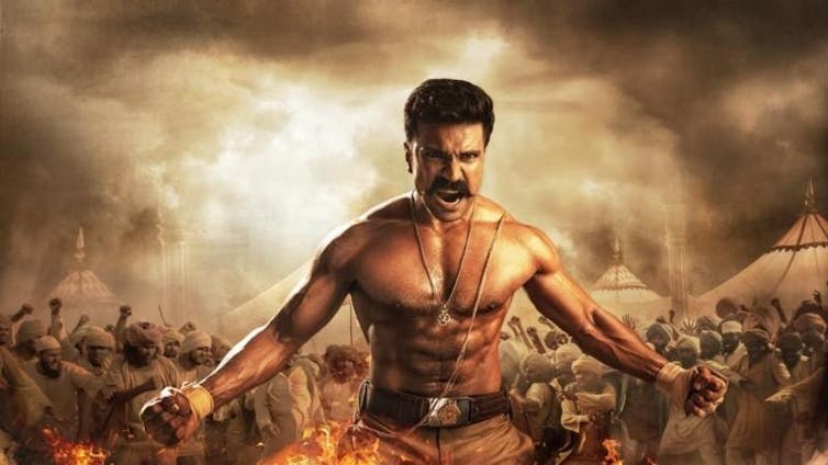 A muscular, shirtless, man holds his arms out in a position of strength