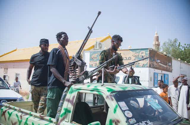 Men on the back of a truck with large guns.