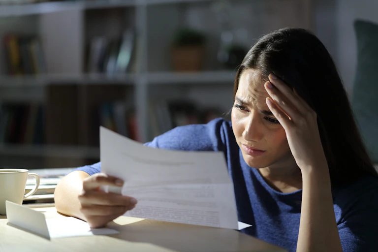 Une jeune fille lit un courrier avec un air ennuyé