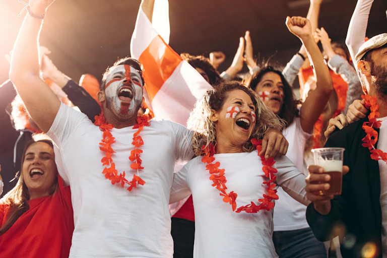 Fans dressed in England colours celebrating at a match