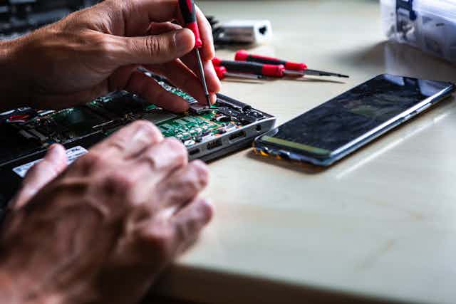 man repairing electronics board from a laptop