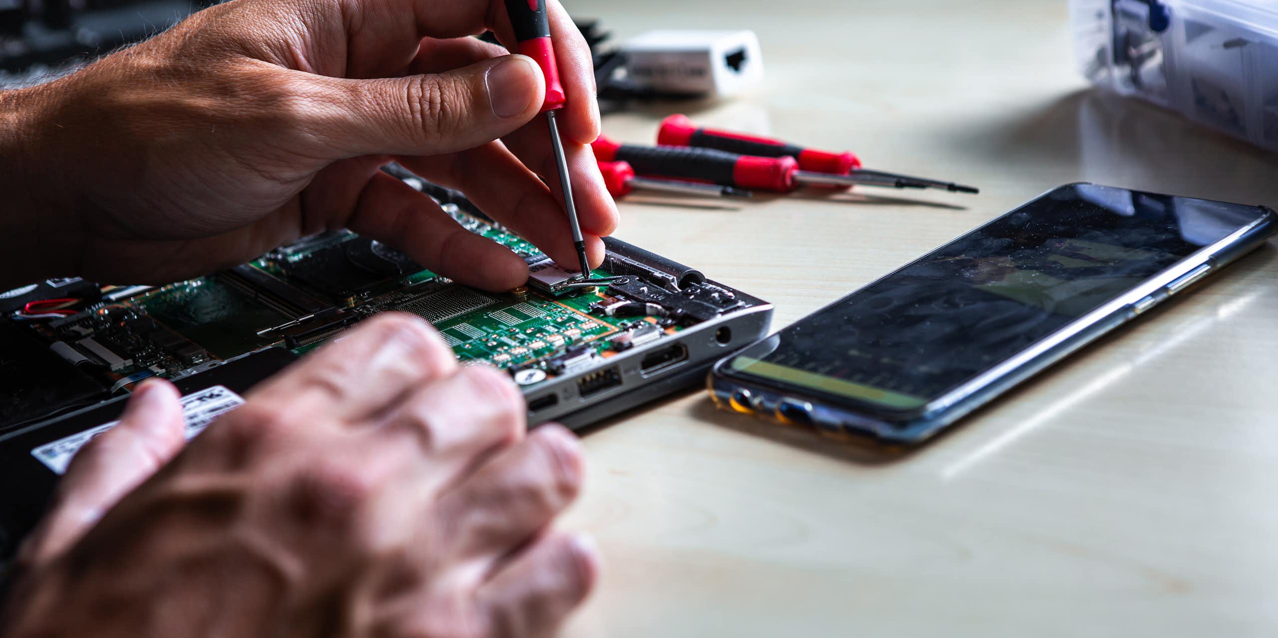 man repairing electronics board from a laptop
