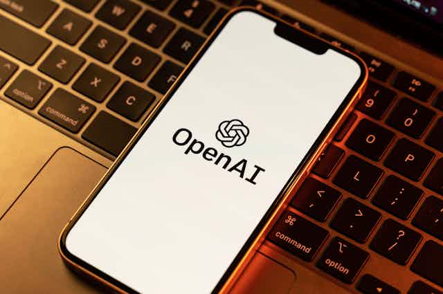 An iPhone displaying OpenAI logo on top of a laptop keyboard