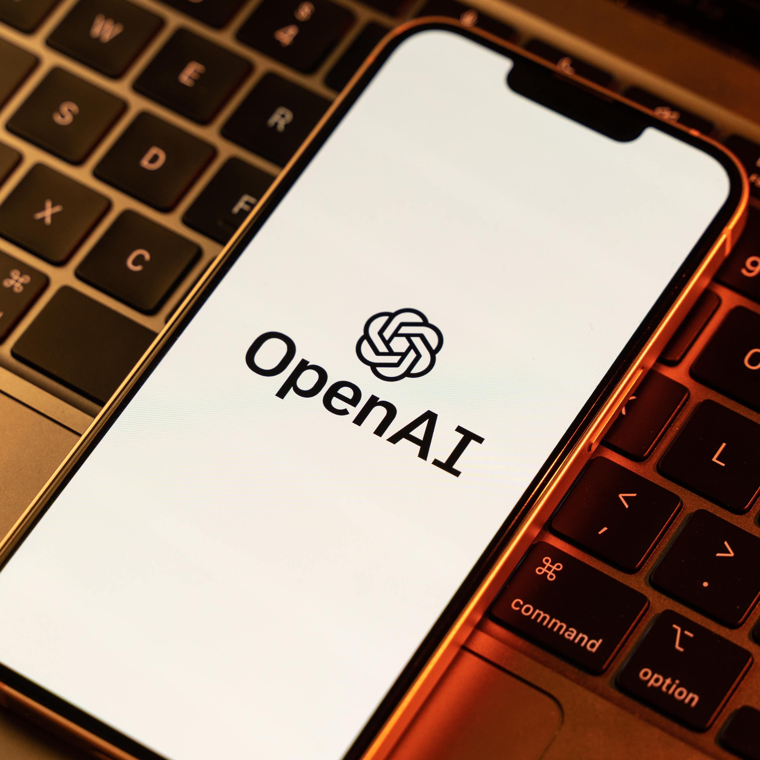An iPhone displaying OpenAI logo on top of a laptop keyboard