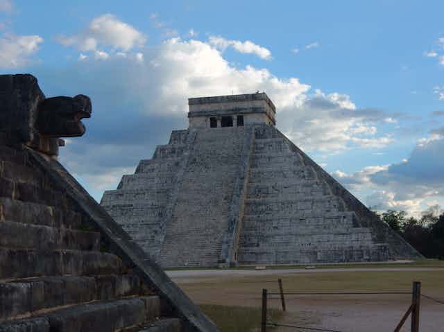 A low angle view of a pyramid with an angular top and large stairs leading up to it.
