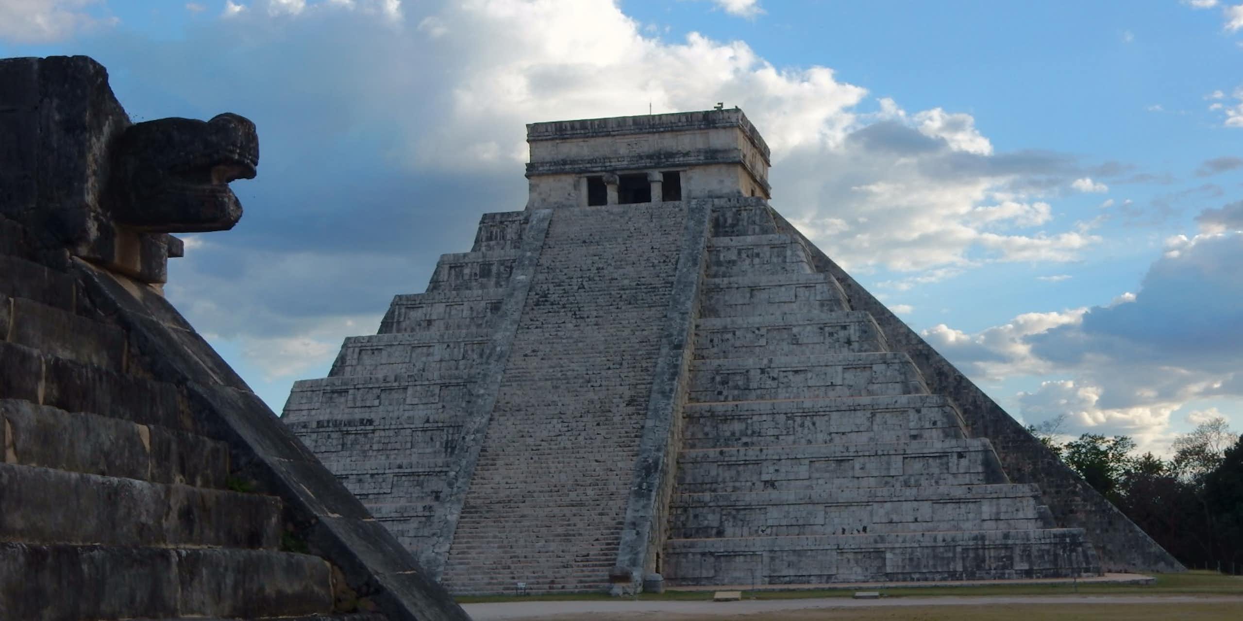 A low angle view of a pyramid with an angular top and large stairs leading up to it.