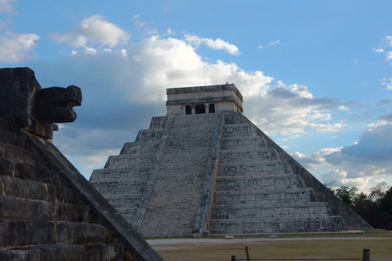 A low angle view of a pyramid with an angular top and large stairs leading up to it.