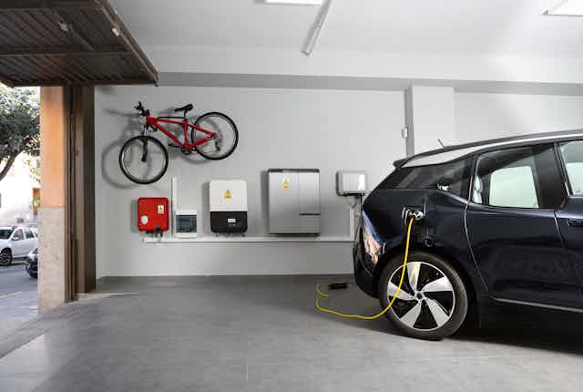 Home battery and EV charging station in a garage, with a bike stored on the wall