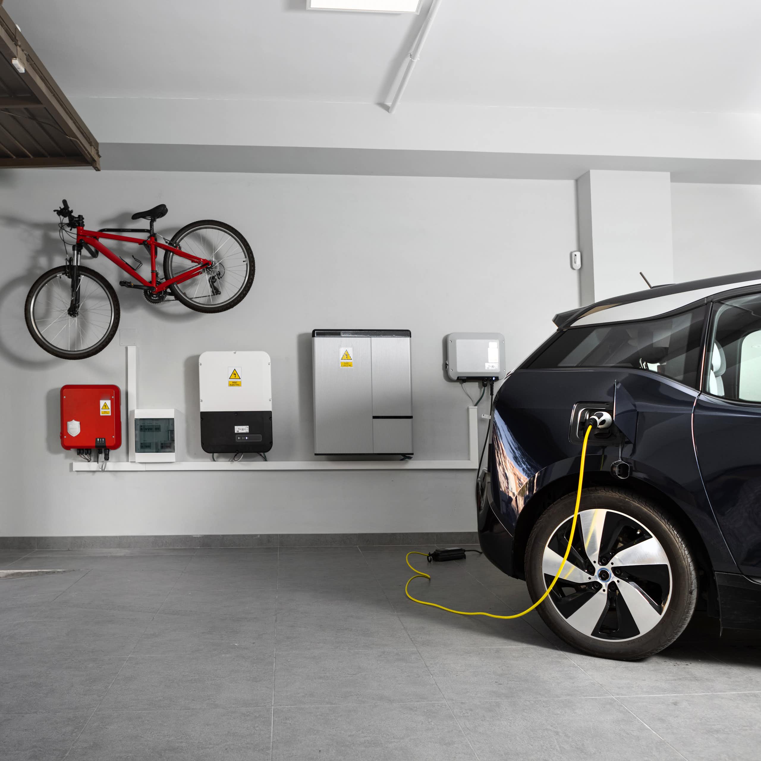 Home battery and EV charging station in a garage, with a bike stored on the wall