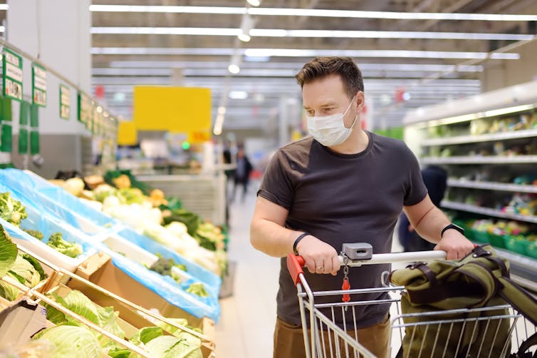 A man in a supermarket wearing a mask.
