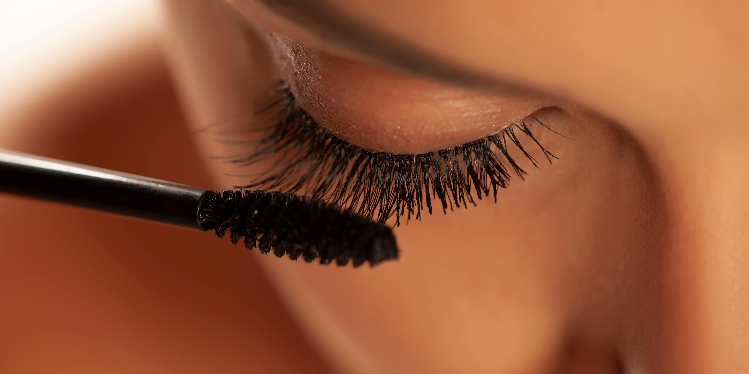 close up of woman applying bacl mascara makeup to eyelashes