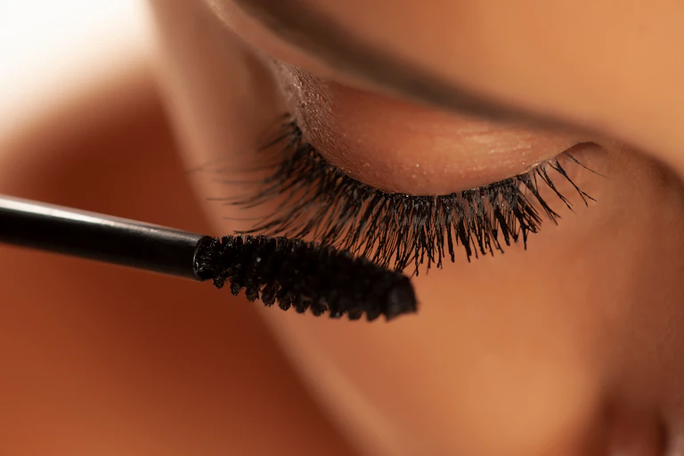 close up of woman applying bacl mascara makeup to eyelashes