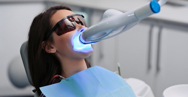 Woman getting her teeth whitened at a dentist.