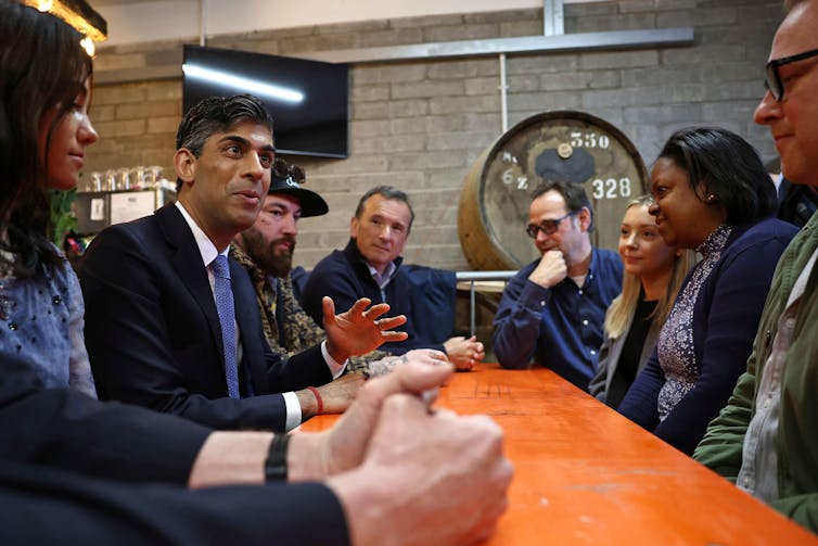 Rishi Sunak talking to voters around a table.