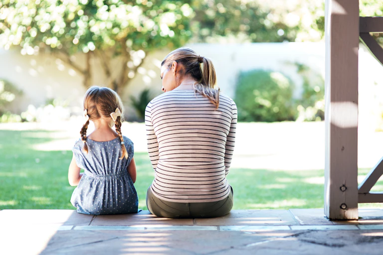 Rearview shot of a young woman and her daughter having a conversation on the porch.